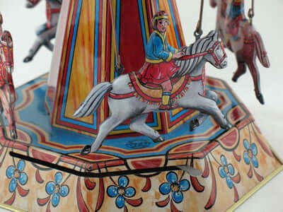 Detailaufnahme des Blech Pferdekarussells mit reitendem Jungen und buntem Design, nostalgisches Sammlerstück aus Metall.