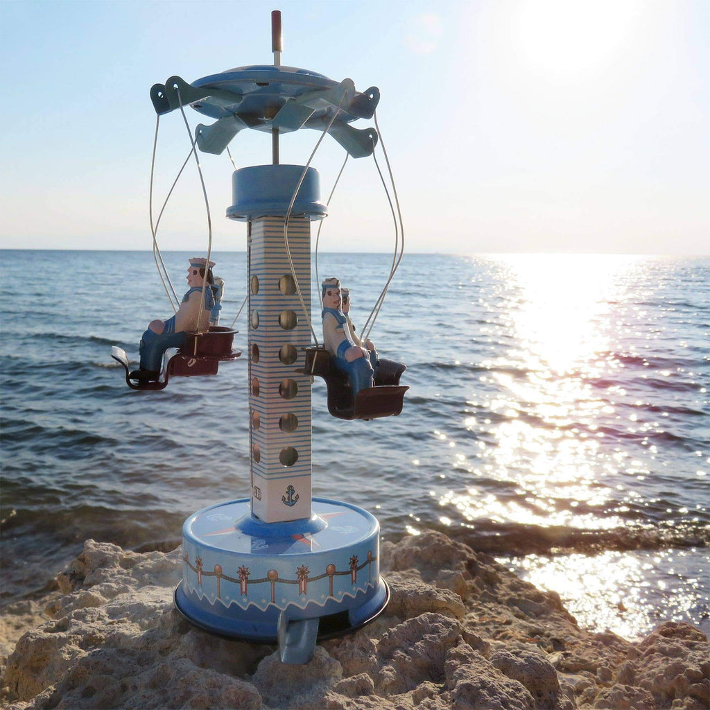 Handaufgezogenes Blechkarussell Matrosen – Nostalgisches Vintage Spielzeug an einem sonnigen Strand