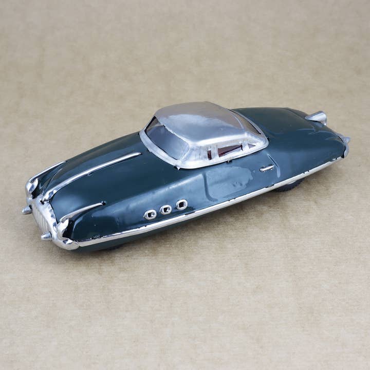 Retro Blechspielzeug 50er Jahre grüner Rennwagen mit Aufziehschlüssel auf braunem Hintergrund